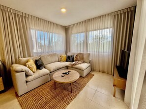 Ein Wohnzimmer mit Ecksofa, Couchtisch und Flachbildfernseher.