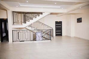 A spacious interior with a staircase, a door labeled 'MILAN', and a framed picture on the wall. - IBK's Hotels and Suites (Port Harcourt)