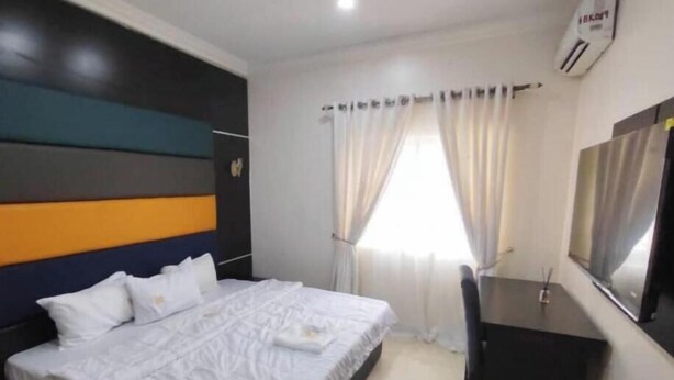 Una habitación de hotel con cama, escritorio, espejo y ventana con cortinas.