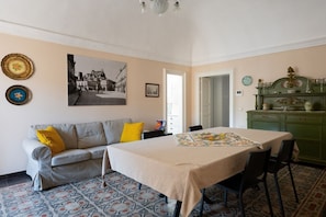 Ein Zimmer mit einer Couch, einem Esstisch und einem grünen Schrank.