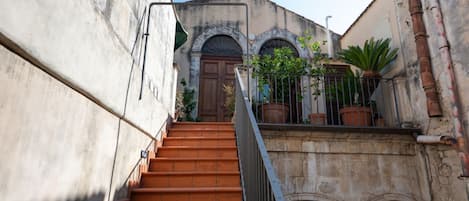 A staircase leading to a building with arched windows and a door.