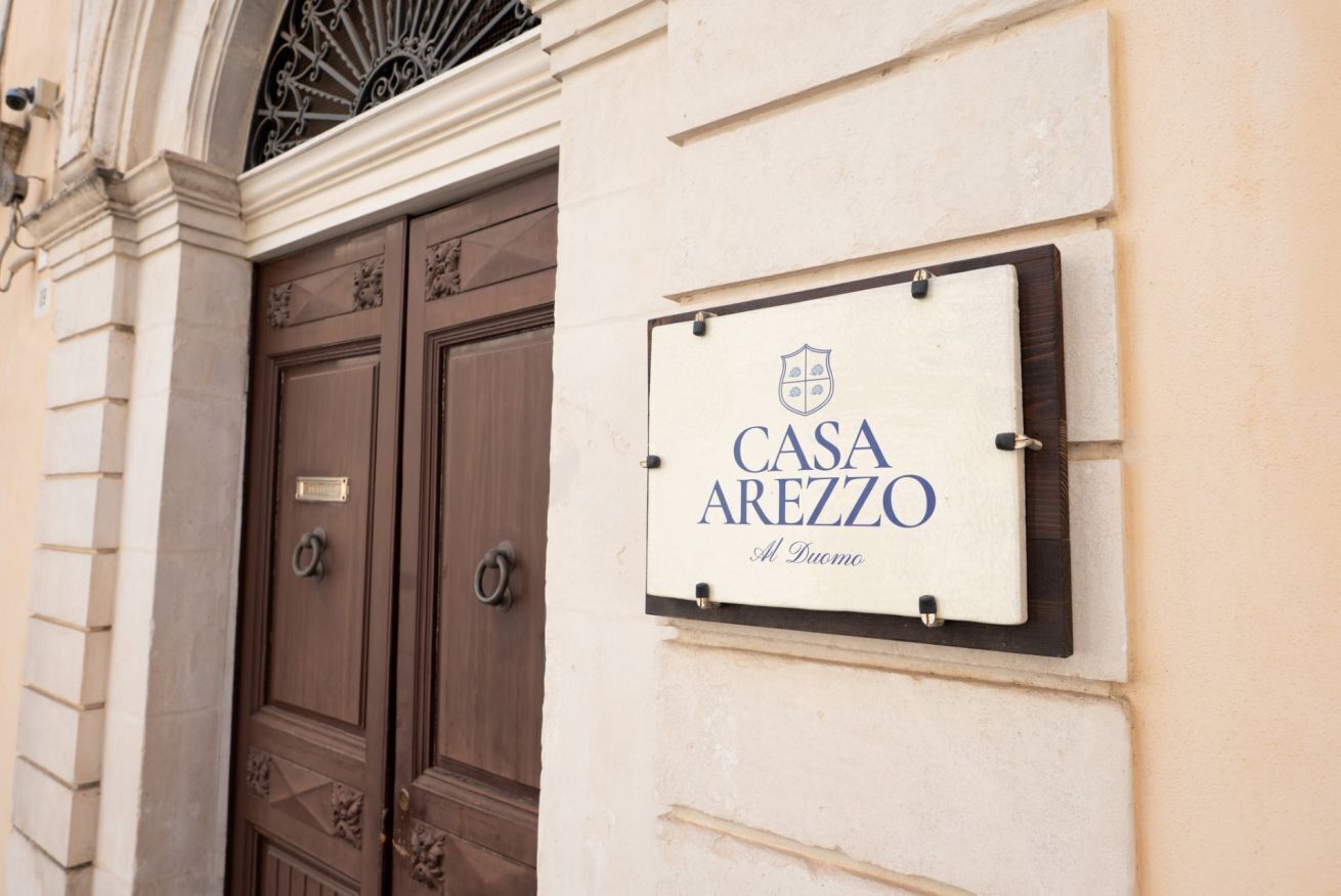 Une enseigne indiquant le nom de l’hôtel : « CASA AREZZO, près du Duomo ».