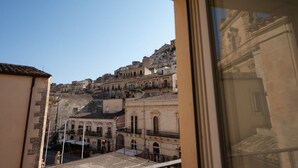 A view of a historic cityscape with buildings of varying heights and architectural styles, viewed from a window. - GuestHost - Casa Arezzo al Duomo (Modica)