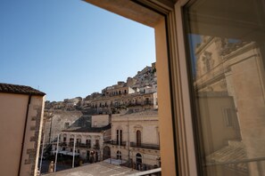 A view of a historic cityscape with buildings of varying heights and architectural styles, viewed from a window. - GuestHost - Casa Arezzo al Duomo (Modica)