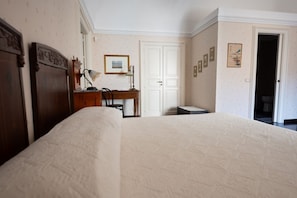 Ein Schlafzimmer mit einem großen Bett, einem Schreibtisch, einem Stuhl und einer Tür.