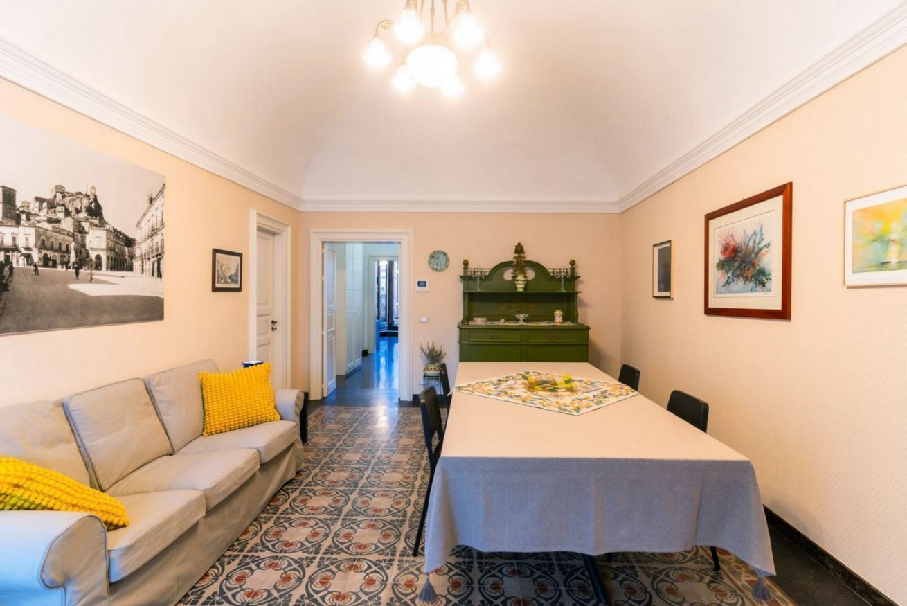 Un coin repas avec une table dressée pour quatre personnes, un canapé avec des coussins et un sol à motifs.