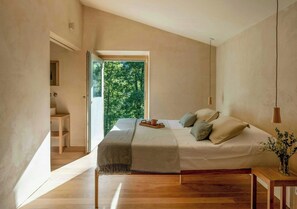 A bedroom with a bed, bedside table, and a view of greenery outside. - Designed and renovated villa with mountain views (Selaya)