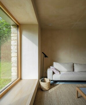 A modern living room with a large window, a sofa, a floor lamp, and a woven basket. - Designed and renovated villa with mountain views (Selaya)
