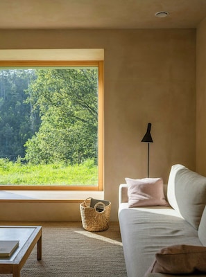 A room with a large window, a sofa, a lamp, and a woven basket. - Designed and renovated villa with mountain views (Selaya)