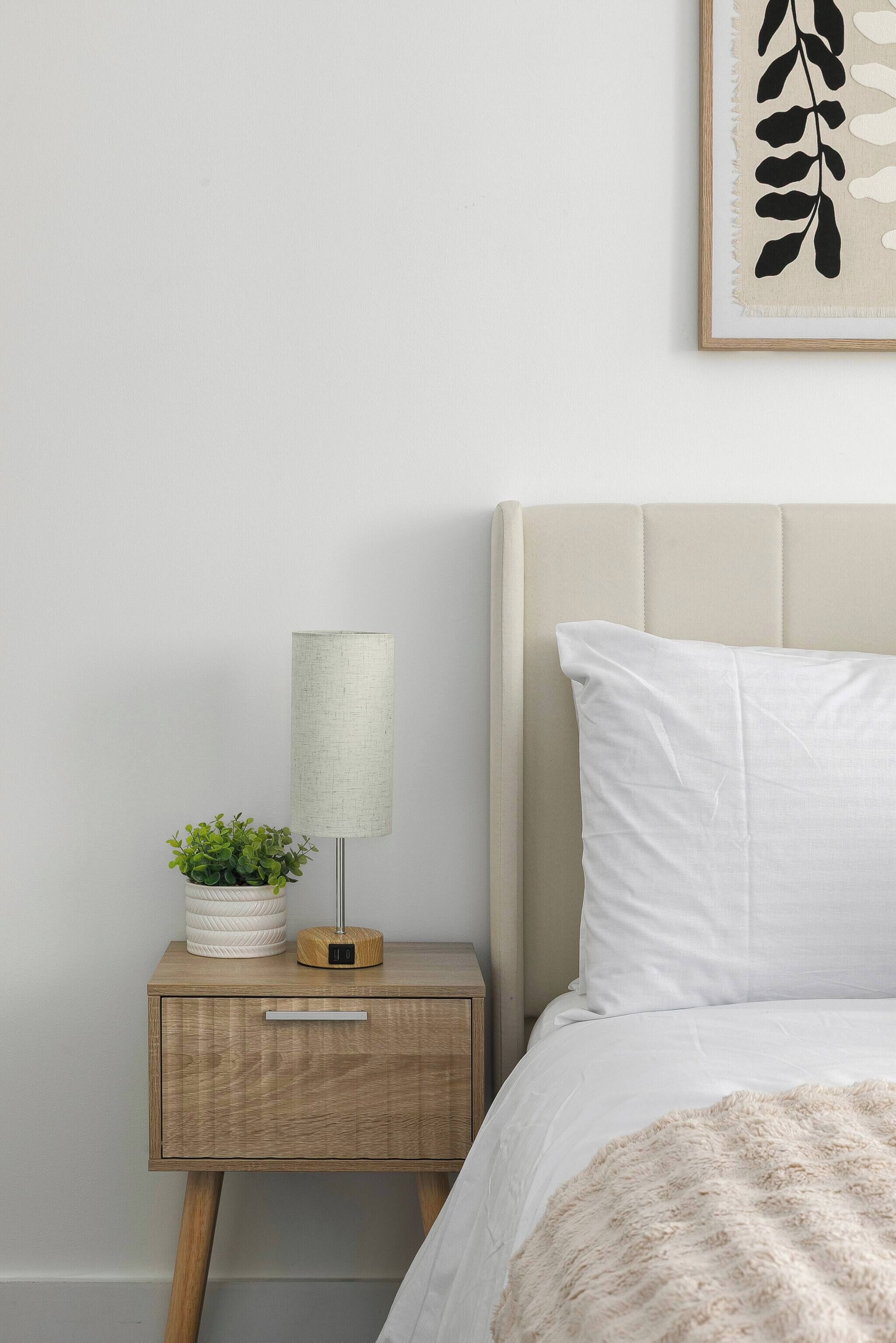 A neatly made bed with a white pillow and a fluffy white blanket.