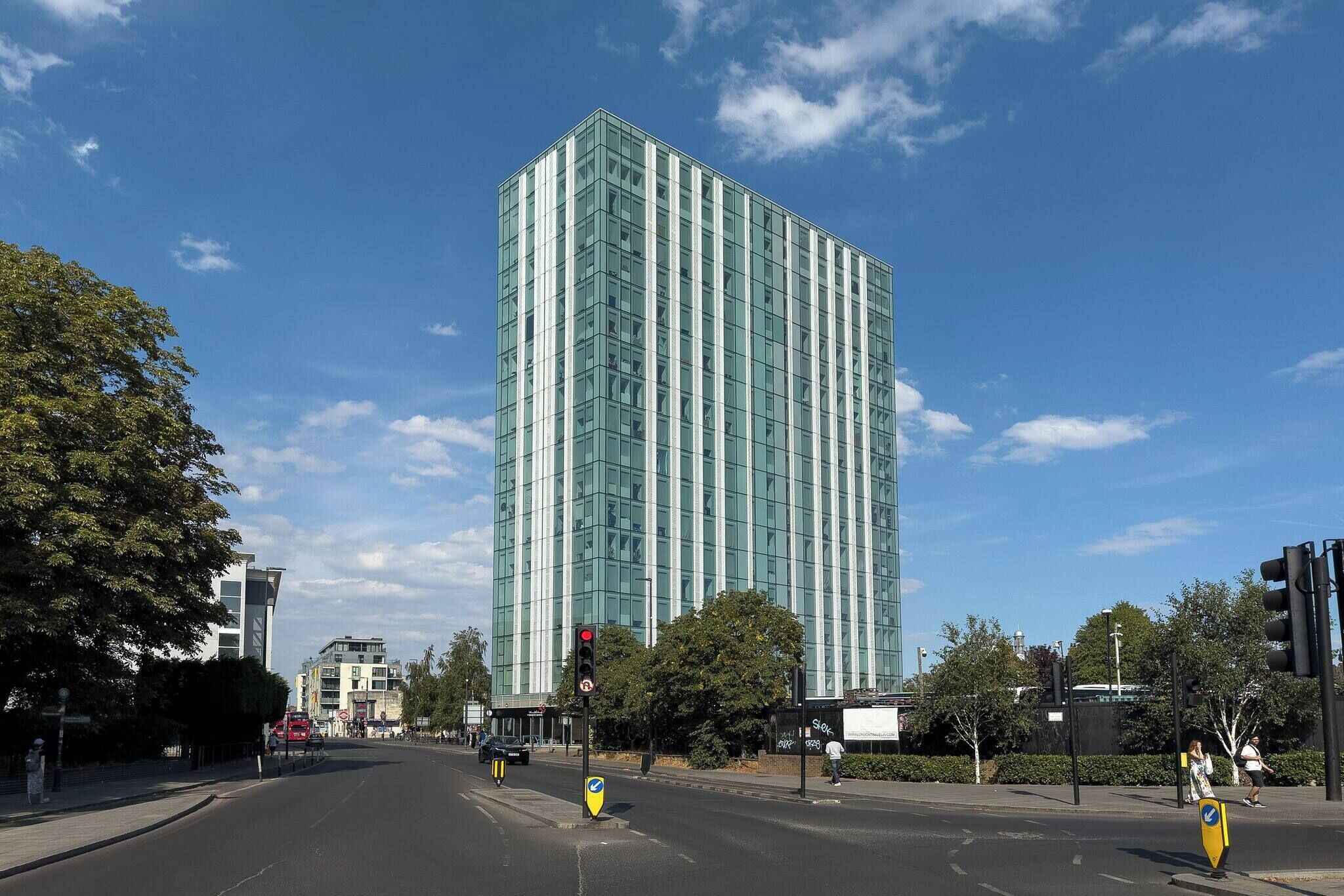 A modern building with a glass facade, a clear sky, and a pedestrian crossing.