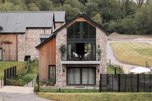 Ein zweistöckiges Steinhaus mit Balkon, einer Holztür und einem gepflasterten Weg.