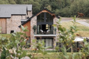 Ein zweistöckiges Gebäude mit einer Steinfassade, großen Fenstern und einem Holzbalkon.