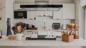 Una cocina moderna con armarios blancos, un microondas negro y una campana extractora de acero inoxidable.