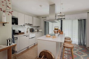 Una cocina moderna con armarios blancos, una isla central y taburetes de bar.