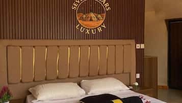 A hotel room with a large bed, a headboard with vertical slats, an air conditioning unit, and a logo on the wall.