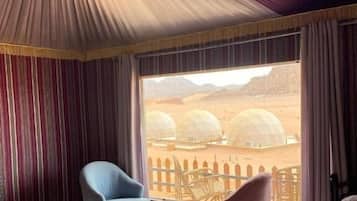 Una habitación de hotel con un ventanal grande, una cama, una silla y una mesita.