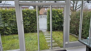 A conservatory with a glass door leading to a garden.