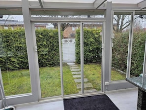 Un invernadero con una puerta de cristal que da a un jardín.