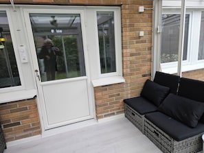 A room with a white door, a brick wall, and a black wicker sofa with cushions. - Unic House, Feeling Calmness in Malmö City (Malmö)