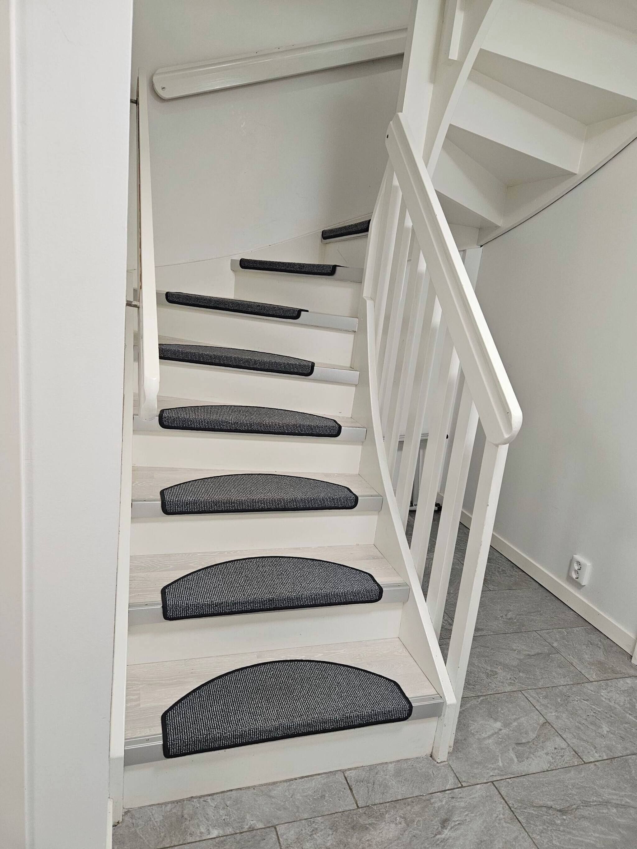 A staircase with white railings and black non-slip treads.