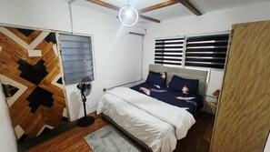 A bedroom with a bed, a standing fan, a window with blinds, and a ceiling fan. - 1-BR Quiet  Private Stay Peaceful Atmosphere (Accra)