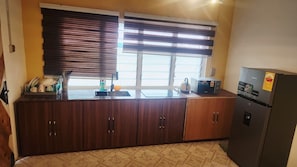Eine Küche mit Holzschränken, einem Spülbecken, einem Wasserkocher und einem Kühlschrank.