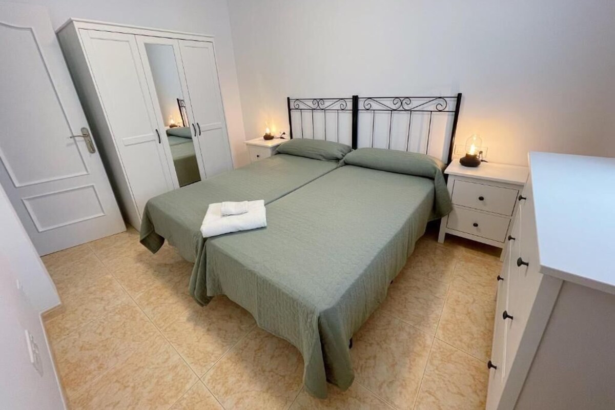 Un dormitorio con cama, mesitas de noche, armario y espejo.