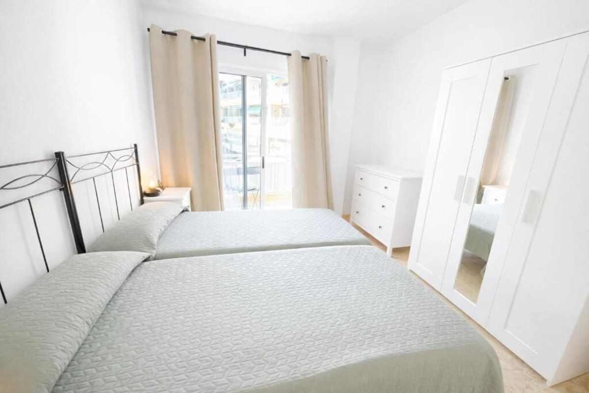 Un dormitorio con dos camas, un armario y un balcón.
