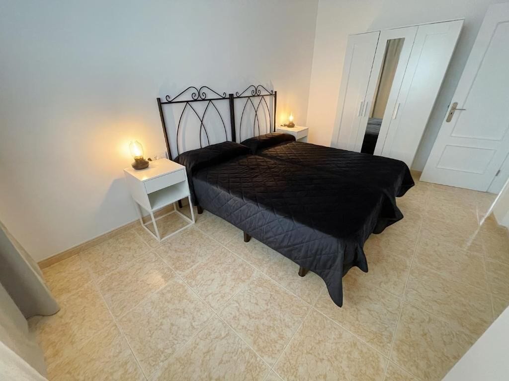Un dormitorio con una cama, mesitas de noche y un armario.