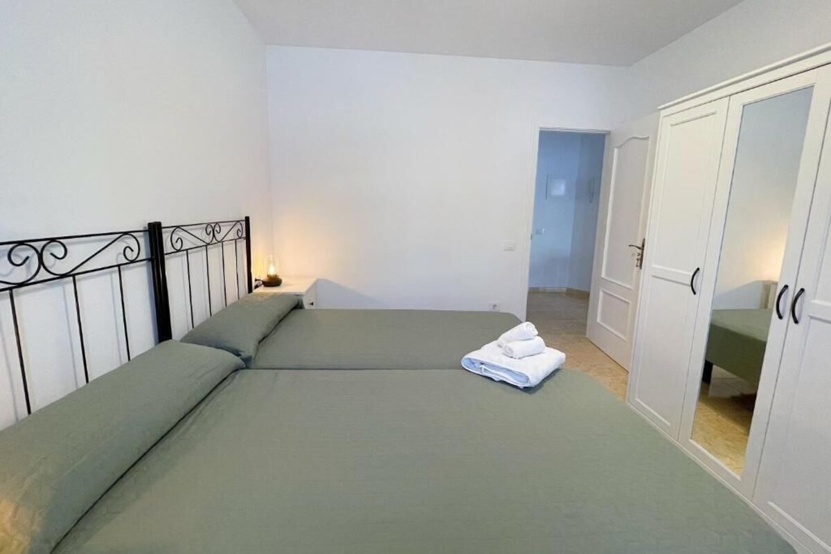 Una habitación con dos camas, un armario y una puerta que da a otra habitación.