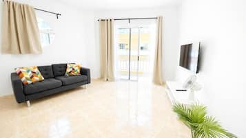 Una sala de estar moderna con un sofá, un televisor de pantalla plana, un ventilador y una planta en maceta.