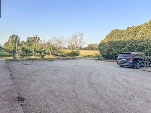 A gravel parking area with a car parked on the right. - Dalia Apartment - Garzolè Farmstay (Castelfranco Emilia)