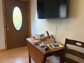 A wooden desk with a television mounted on the wall, a horse figurine, and various items on the desk.