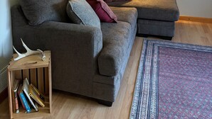 A modern living room with a grey sectional sofa, a standing floor lamp, and two wall-mounted Adirondack chairs. - 3-Bedroom Getaway Between Saratoga Springs & Lake George (Gansevoort)