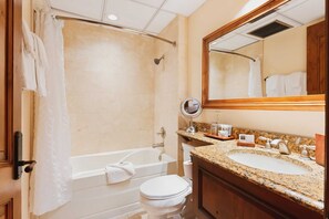 Et badeværelse med badekar, toilet, håndvask og et spejl.