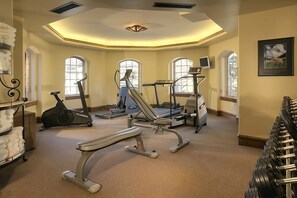 Et fitnessrum med løbebånd, crosstrainere og håndvægte.