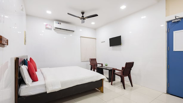Habitación de hotel con cama, escritorio, silla, televisión y aire acondicionado.