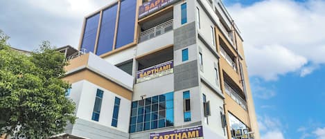 A multi-story hotel with a sign for 'Hotel Sapthami Luxury Rooms & Mini Function Hall'.
