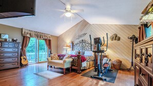Ein Schlafzimmer mit einem Bett, einer Gitarre, einem Deckenventilator und einem Trainingsgerät.
