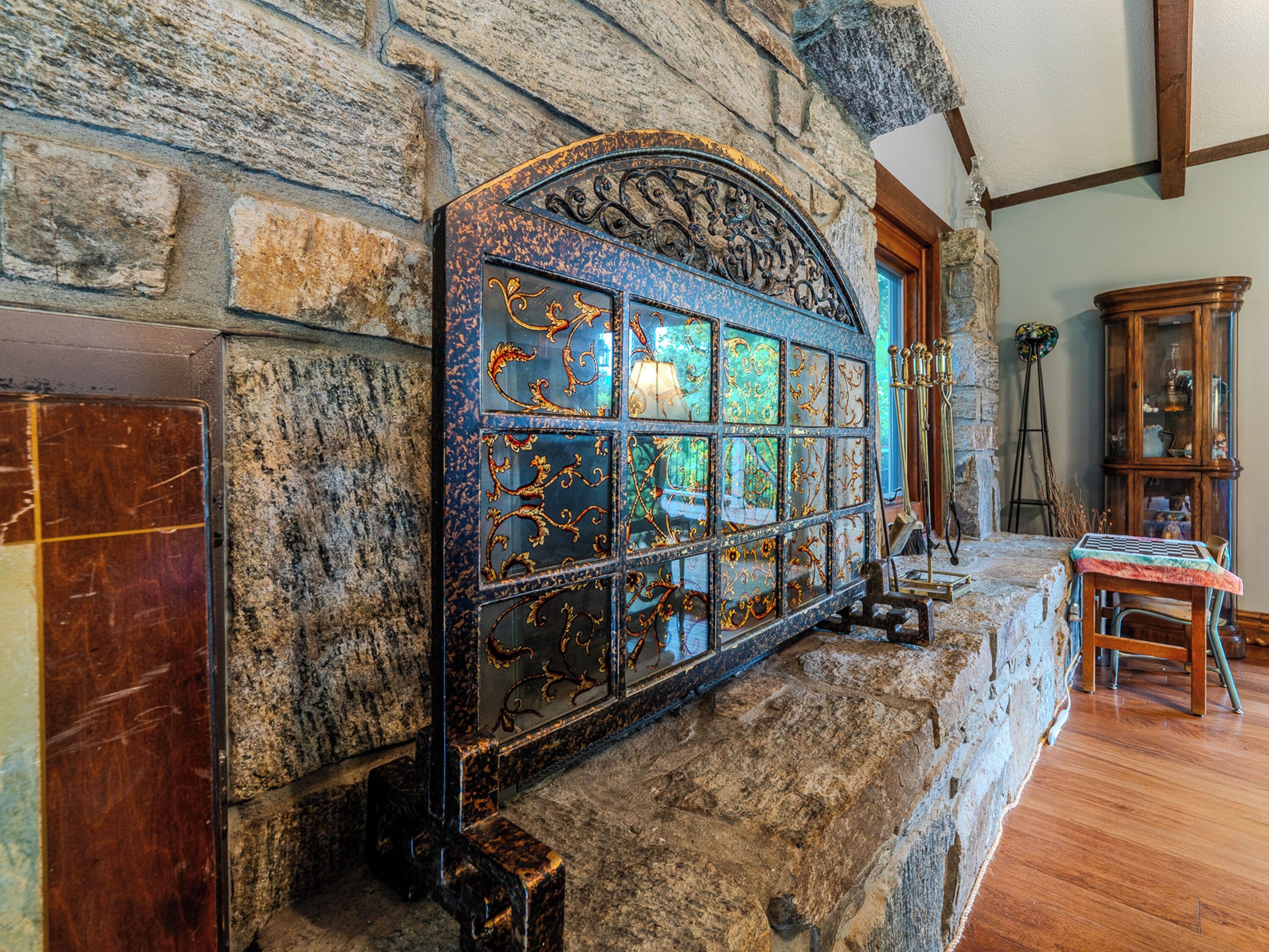 A stone wall with a decorative metal grill and a wooden cabinet.