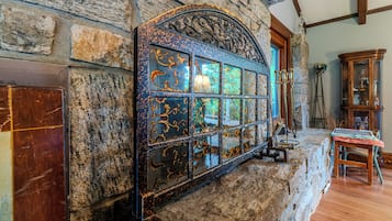 Un mur en pierre agrémenté d’une grille métallique décorative et d’une armoire en bois.