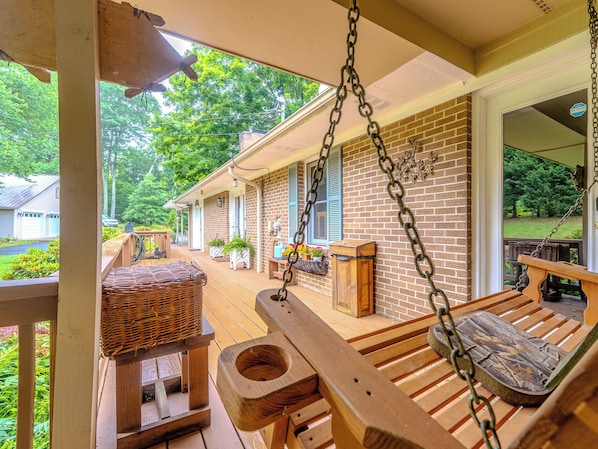 A wooden porch with a swing, a wicker chair, and a wooden bench. - Beautiful Home on Mountainous Tree Farm (Newland)