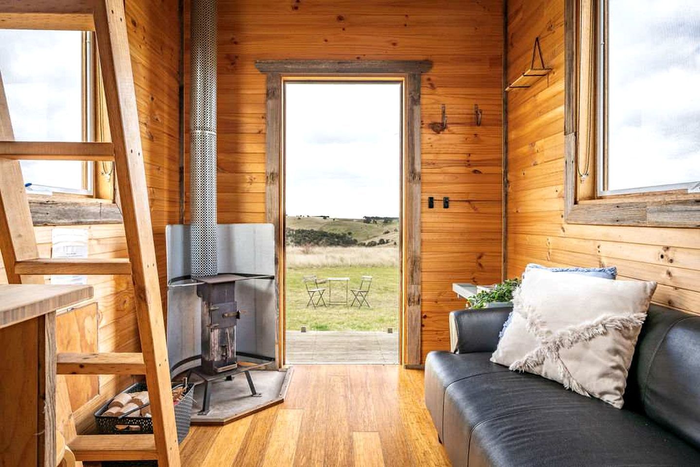 A cozy cabin interior with a wooden exterior, a fireplace, a sofa, and a view of the outdoors.