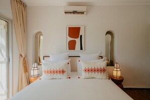 Ein Hotelzimmer mit einem Bett, zwei Nachttischen, einer Wand-Klimaanlage und einem Bild.