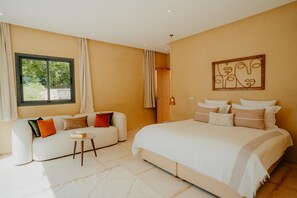 Une chambre d’hôtel avec un lit, un canapé, une petite table et une fenêtre avec des rideaux.