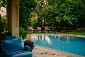 A swimming pool with lounge chairs and greenery in the background. - Kasbah Amaya – 7 bedrooms, swimming pools, hammam & Atlas vue (Marrakech)