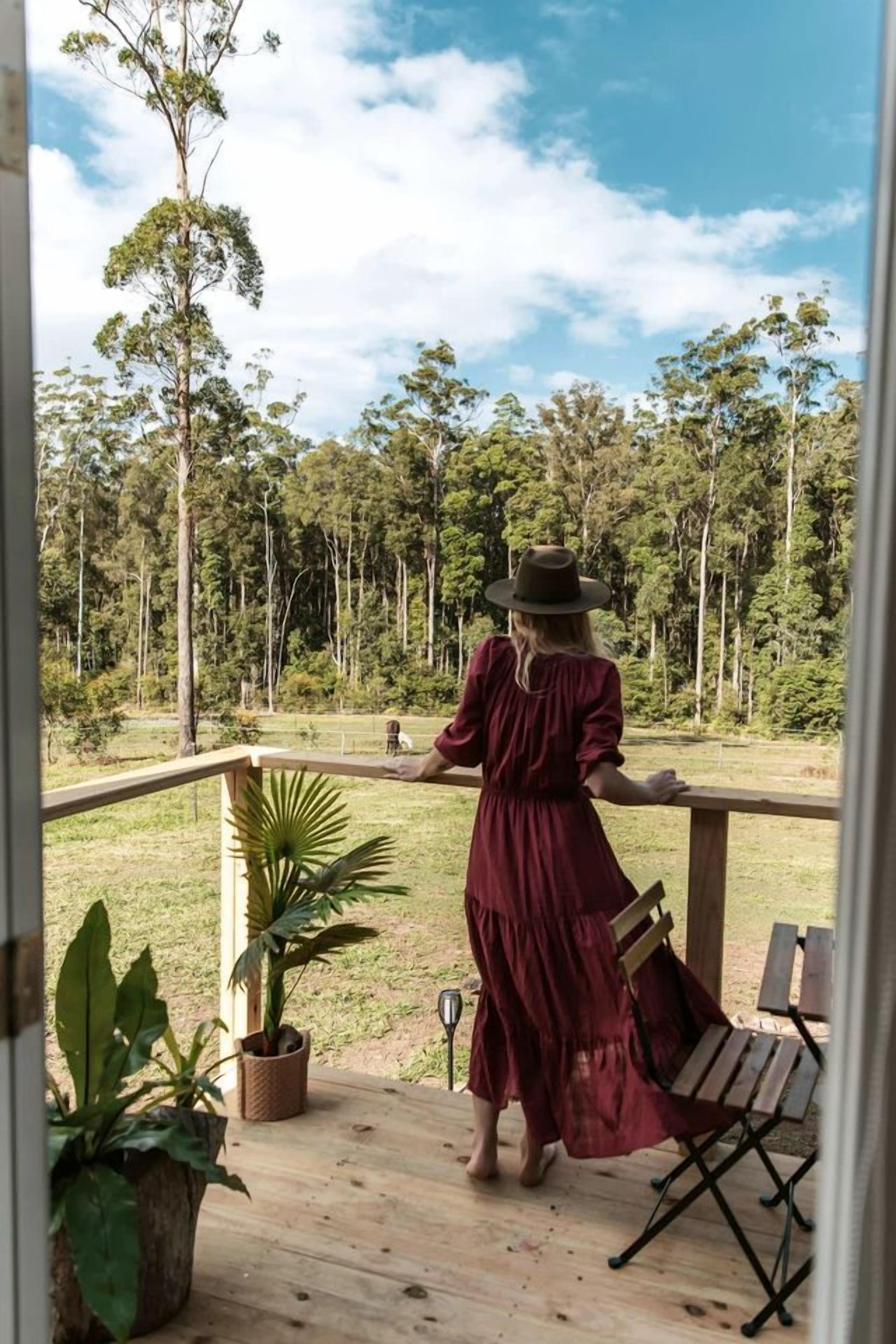 A woman standing on a wooden deck with a view of a forest.