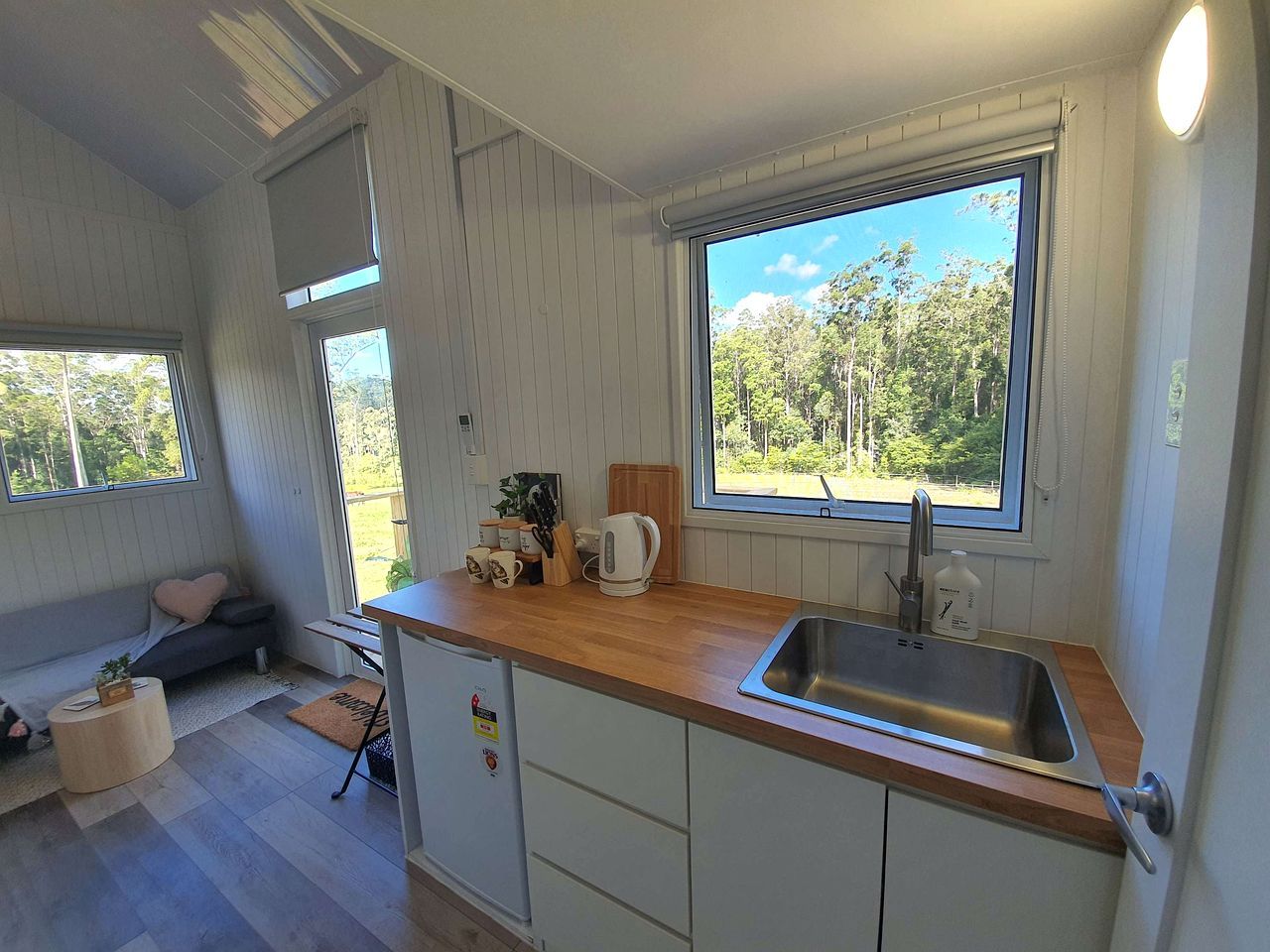 A compact kitchen with a wooden countertop, a sink, and a window with a view of greenery.
