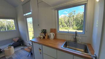 A compact kitchen with a wooden countertop, a sink, and a window with a view of greenery.